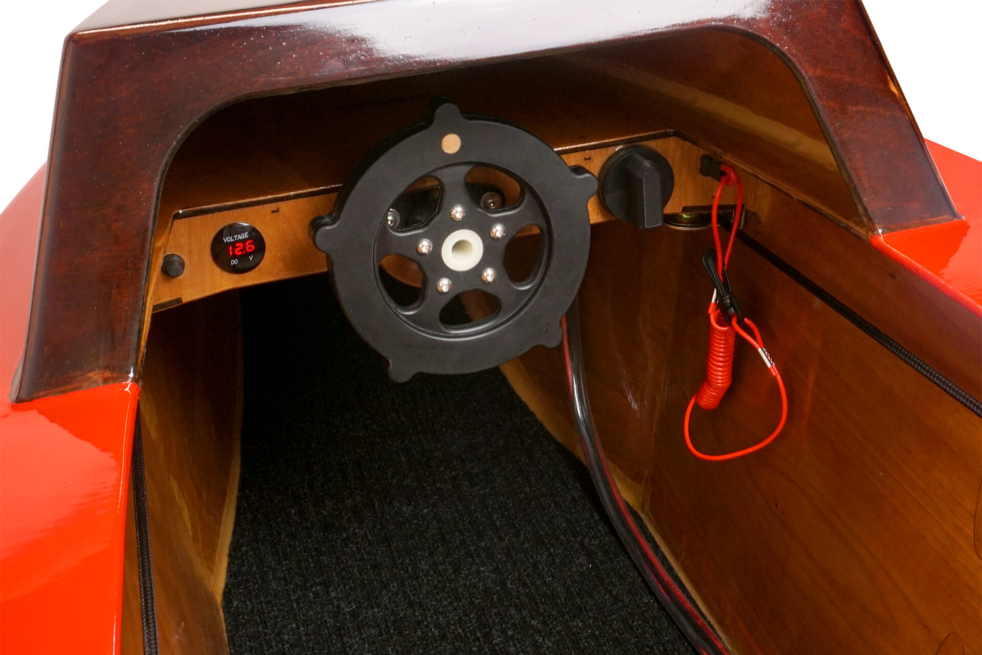 A dashboard view of the mini electric boat, showing off the steering wheel, volt-meter, and dead-man's switch.
