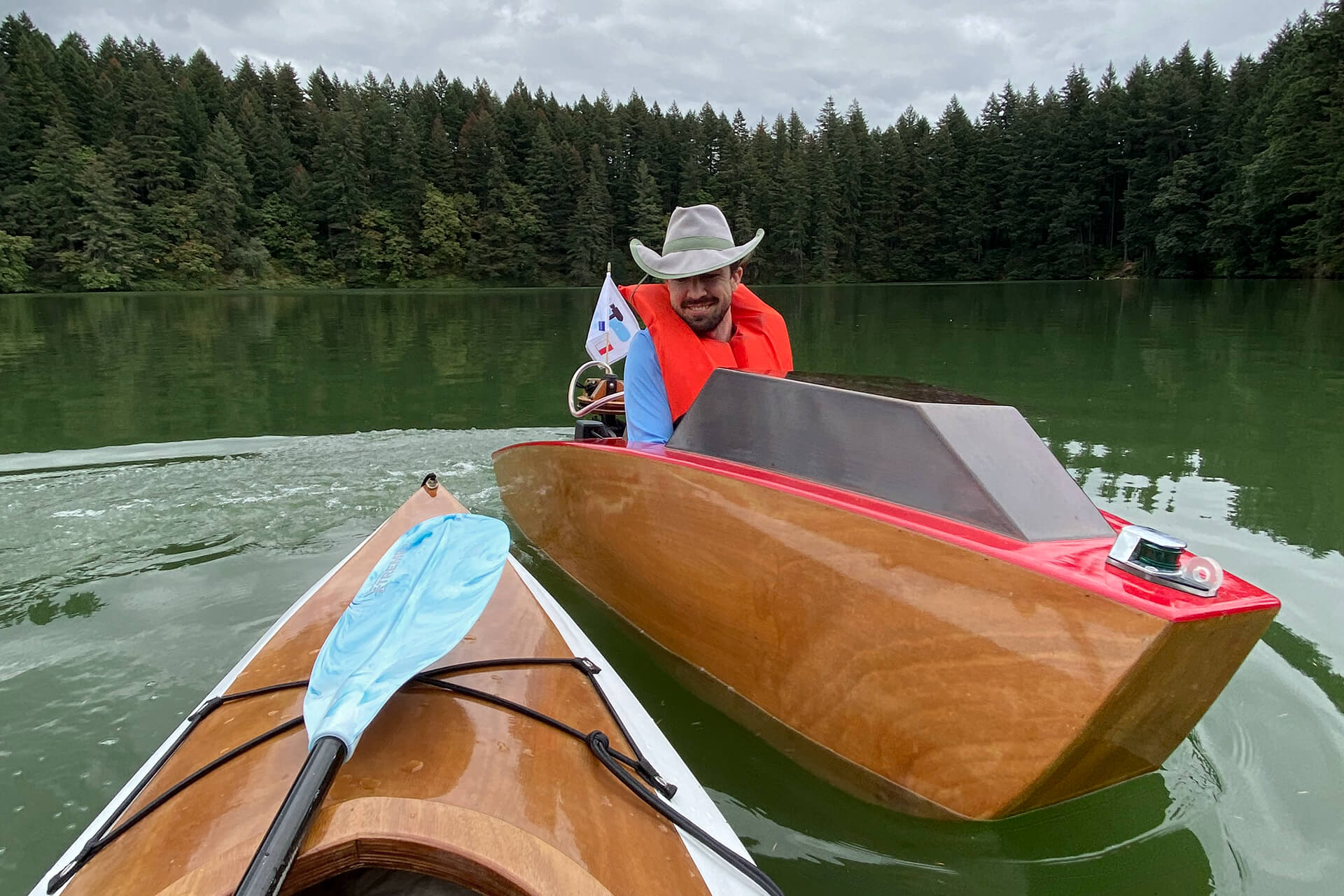 A mini boat gliding by a Chesapeake Light Craft kayak in Round Lake.