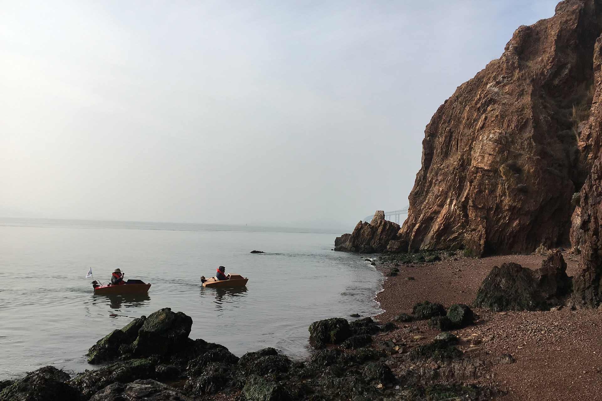 Two mini boats about to land on the shore of red rock island.